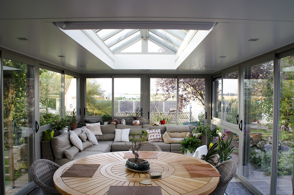 Exemple de véranda moderne : espace lumineux, ouvert sur le jardin, avec baies vitrées aluminium.